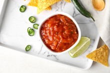 Tray With Bowl Of Tasty Salsa Sauce And Nachos On Light Background