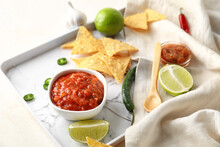 Tray With Bowl Of Tasty Salsa Sauce And Nachos On Light Background