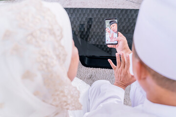 Wall Mural - Muslim old couple doing video call with children