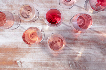 Wall Mural - Pink wine hues, many wineglasses, shot from the top on a wooden background