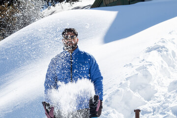 Wall Mural - Handsome man in warm clothing with splashing and spraying snow powder on a cold winter day