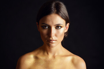 Close-up portrait of young woman with golden makeup.