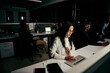 © StratfordProductions - Female employee busy in her work on laptop in office and with colleagues at background