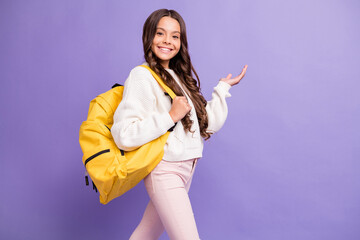 Poster - Photo of young beautiful smiling cheerful good mood girl wear yellow bag demonstrate copyspace isolated on purple color background