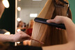 © New Africa - Stylist straightening woman's hair with flat iron in salon