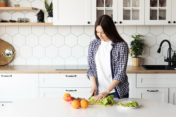 Girl preparing fresh salad in the kitchen