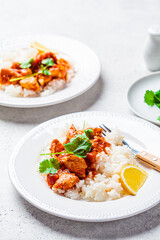 Wall Mural - Fried chicken in tomato sauce with rice on white plate, gray background.