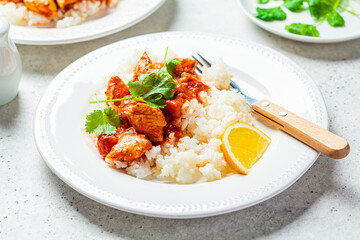 Wall Mural - Fried chicken in tomato sauce with rice on white plate, gray background.