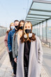© Iryna - Young diverse unemotional people stand in a row, one after another, in queue waiting for medical help, wearing medical masks on face, outdoor.