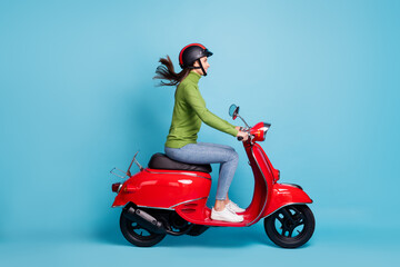 Wall Mural - Full length side profile photo portrait of woman in helmet driving red scooter isolated on pastel blue colored background