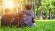 two asian man friends sitting on green grass in the park, encouraging, comforting his friend and looking in the same direction