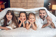 © zinkevych - Smiling family in white robes lying in bed and having fun