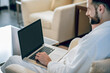 © zinkevych - Young bearded man in a white bath robe sitting with a laptop