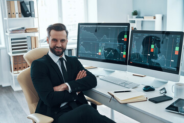 Canvas Print - Good looking young man in formalwear smiling and looking at camera while working in the office