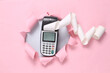 © splitov27 - Payment terminal through the torn hole pink paper.
