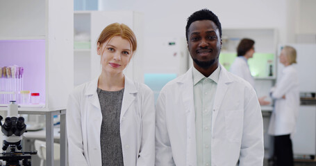 Portrait of multiethnic young scientists smiling at camera in modern laboratory