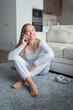 © shapovalphoto - woman sit on floor at home, holding smartphone, smiling face