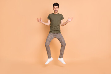 Sticker - Full length body size photo of jumping funny man smiling wearing casual clothes isolated on pastel beige color background