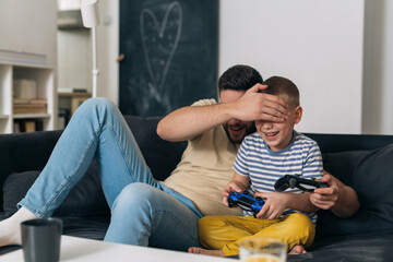 Wall Mural - father playing video games with his son. they are sitting in living room