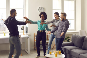 You're finally back. Group of young diverse people excited to meet their friend who's been away for a long time. Happy man spreading arms wide open to hug his friends who he missed so much