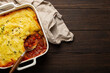 Traditional dish of British cuisine Shepherd's pie casserole with minced meat and mashed potatoes in ceramic baking dish on brown wooden rustic table with spoon from above with space for text