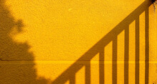 Close-up Of The Railing Shadow On The Yellow Wall, From The Fence On The Yellow Background Of The Building, Minimalism