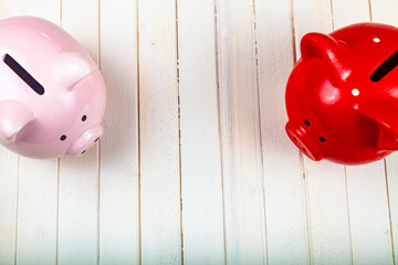 Two pigs piggy banks on a white wooden background.