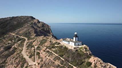 Sticker - Aerial view circling La Revellata lighthouse above the Mediterranean sea near Calvi in the Balagne region of Corsica with snow capped mountains in the distance