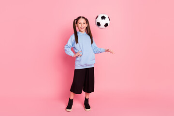 Full length body size photo of schoolgirl in sport outfit throwing ball in air smiling isolated pastel pink color background