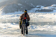 Bicyclist on the coast of Baikal lake in winter. Buguldeika, Irkutsk Region, Russia