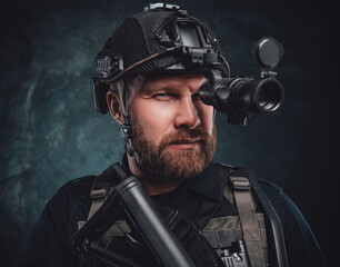 Wall Mural - Martial guy looks in night vision device holding his rifle in dark background