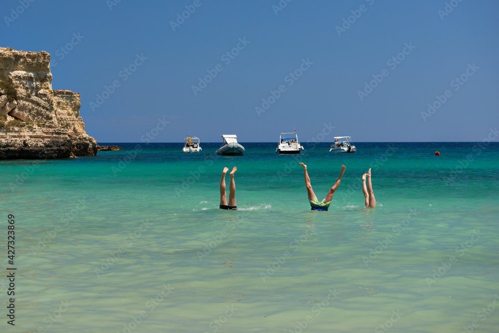 Młodzież aktywnie wypoczywająca w słoneczny letni dzień  nad ciepłym morzem, kąpiele morskie wśród fal. - obrazy, fototapety, plakaty 