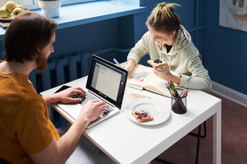 Happy couple sitting at the table while working at home together