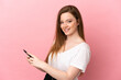 © luismolinero - Teenager girl over isolated pink background sending a message or email with the mobile