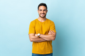 Young handsome man over isolated background keeping the arms crossed in frontal position