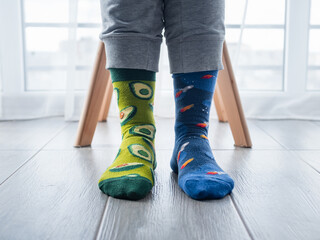 Wall Mural - Two different artistic socks on feet, with avocados on the left and blue space on the right