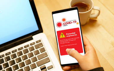 Covid 19 smart Alert application mock up. Close up a woman's hand checking on digital contact-tracing apps on her smartphone it's show 