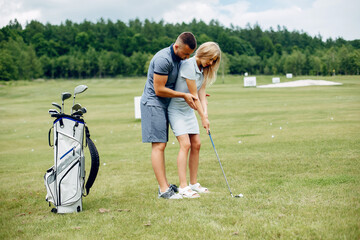 Wall Mural - Beautiful couple playing golf on a golf course