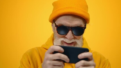 Happy man looking to screen indoors. Mature guy playing mobile game in studio.