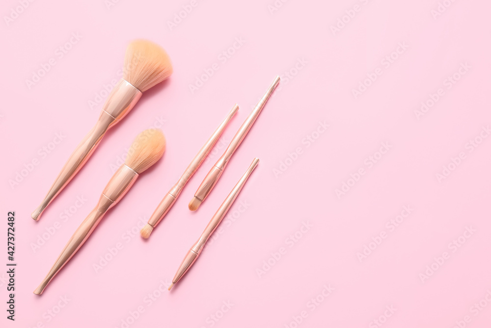 Stylish makeup brushes on color background