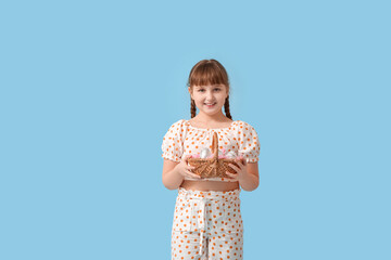 Wall Mural - Cute little girl with basket of chocolate Easter eggs on color background