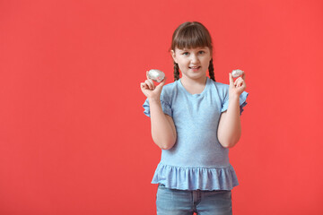 Poster - Cute little girl with chocolate Easter eggs on color background