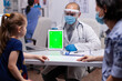 © DC Studio - Doctor with face mask and visor using green screen tablet pc in examination office during coronavirus pandemic. Healthcare physician with chroma key notebook isolated mockup screen
