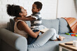 © Drobot Dean - Black happy mother and son hugging and making fun while sitting on sofa