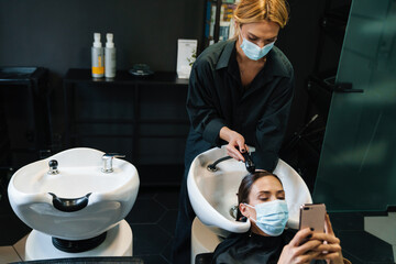 Woman washing her client's hair while doing hairstyle in beauty salon