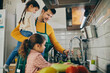 © Drazen - Single father with daughters washing vegetables while preparing food in the kitchen.