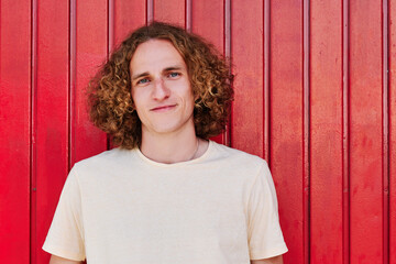 a young man with curly hair and green eyes smiling and looking at camera