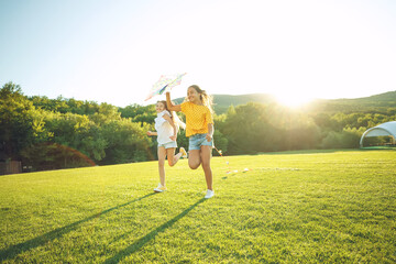 Children play in nature. A group of children runs on the grass in the park with a kite. High quality photo.