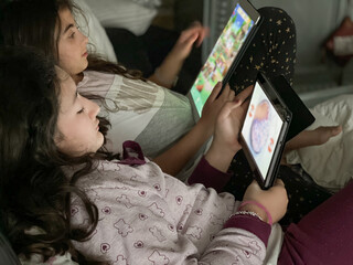 Wall Mural - Two happy young girls playing with tablet at home