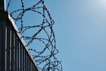 Coiled barbed wire fencing against a blue sky background